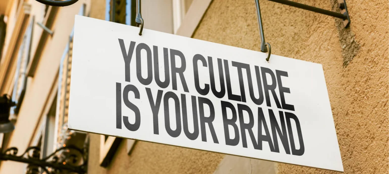 A hanging storefront sign that reads 'Your culture is your brand.'