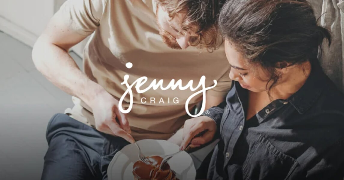A couple sharing a meal together at home, with the Jenny Craig logo overlaid.
