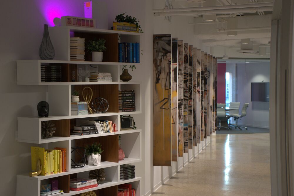Bookshelves styled with books and objects beside a hallway of art panels