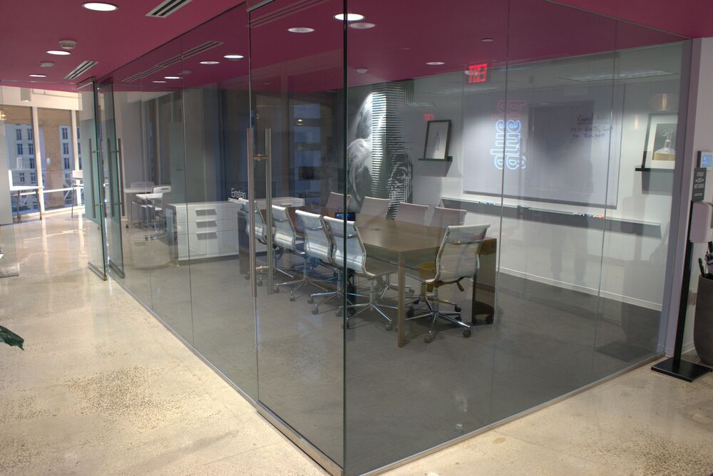 A glass-walled conference room with a magenta ceiling and a long table